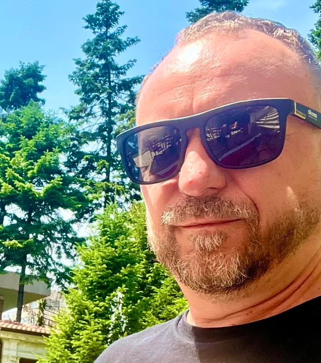 Adam, the site's author, wearing sunglasses in a garden